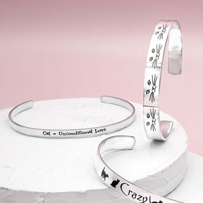 Stainless steel cuff bracelet with the inscription 'Cat, Unconditional Love' surrounded by paw prints.