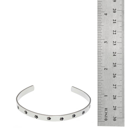 Stainless steel cuff bracelet with a minimalistic pet paw print design, featuring the inscription 'Unconditional Love' on the inside.