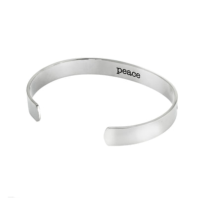 Stainless steel cuff bracelet with a minimalist dolphin jumping silhouette, featuring the inscription 'Peace' on the inside.