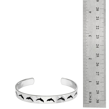 Stainless steel cuff bracelet with a minimalist dolphin jumping silhouette, featuring the inscription 'Peace' on the inside.